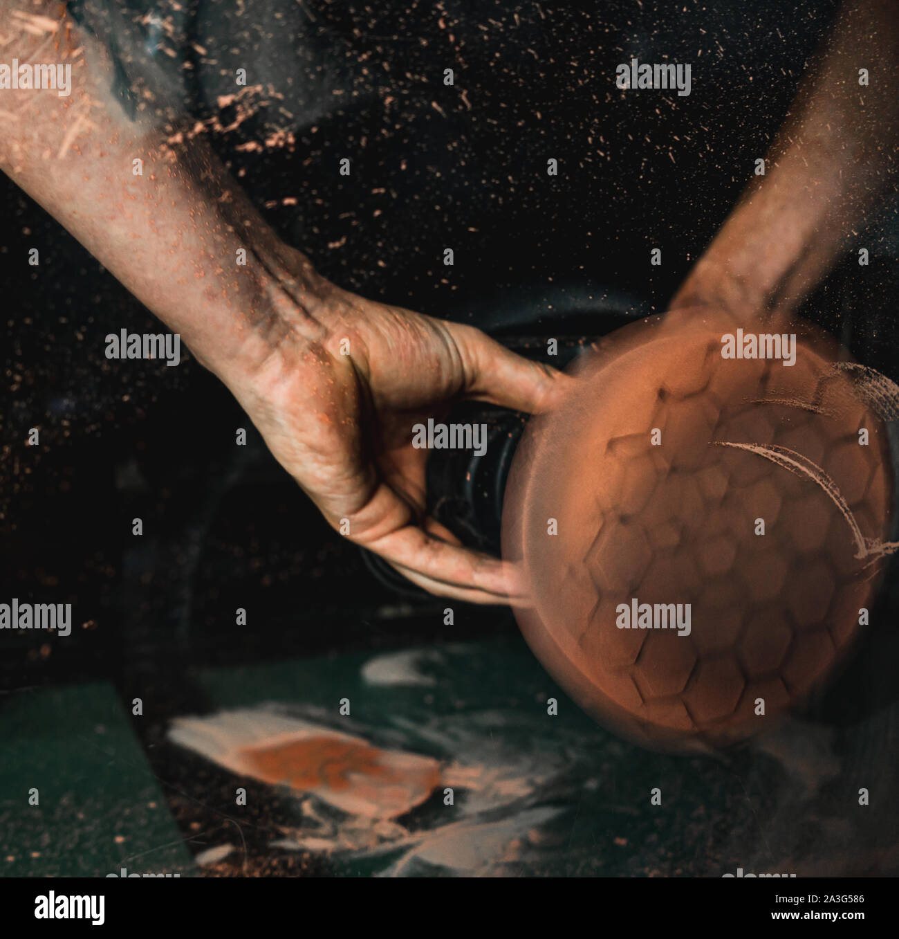 Closeup on mechanic's hands using professional glass polishing tool to