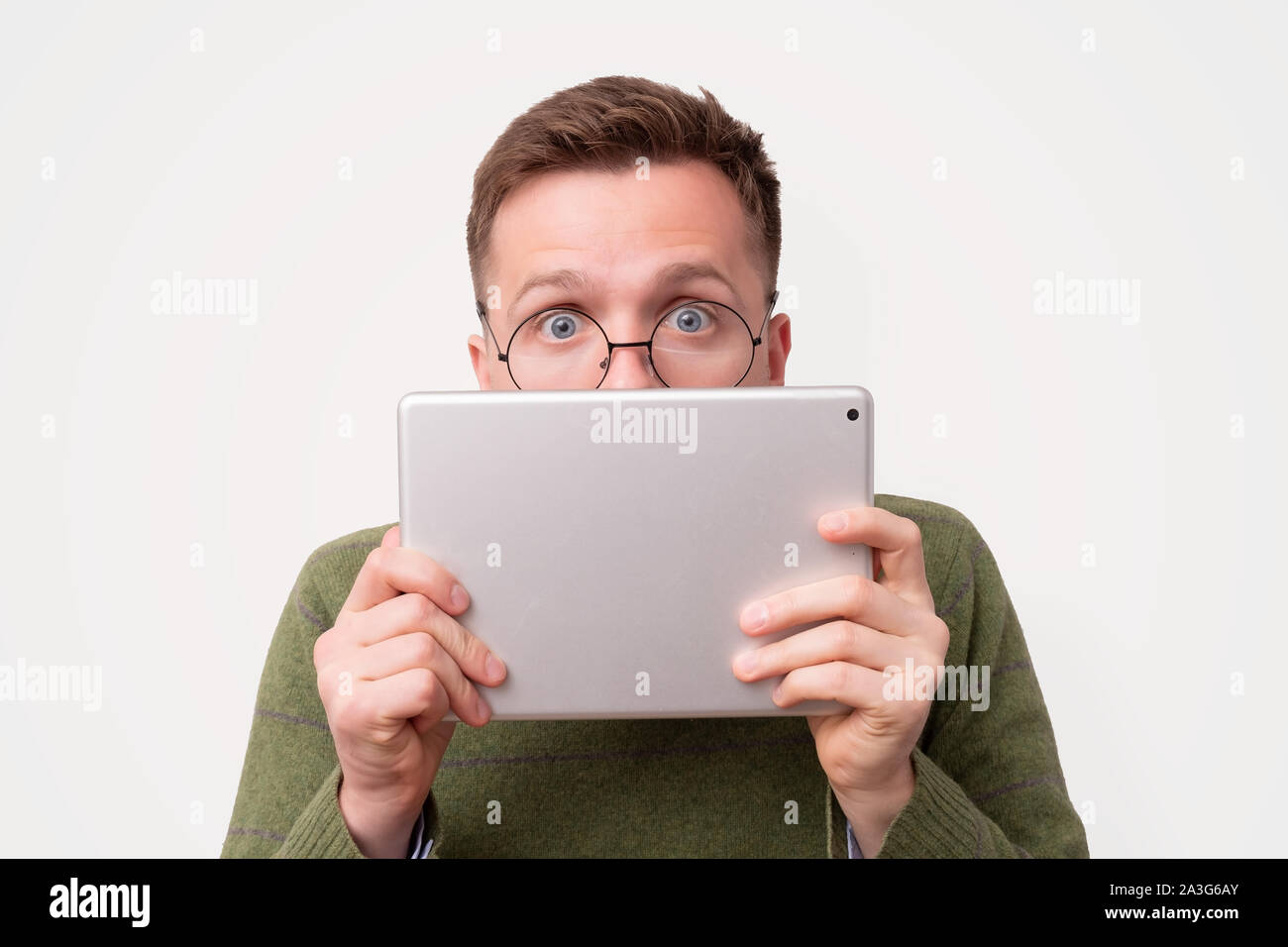 Young guy in funny glasses hiding his face with e-book reader Stock Photo