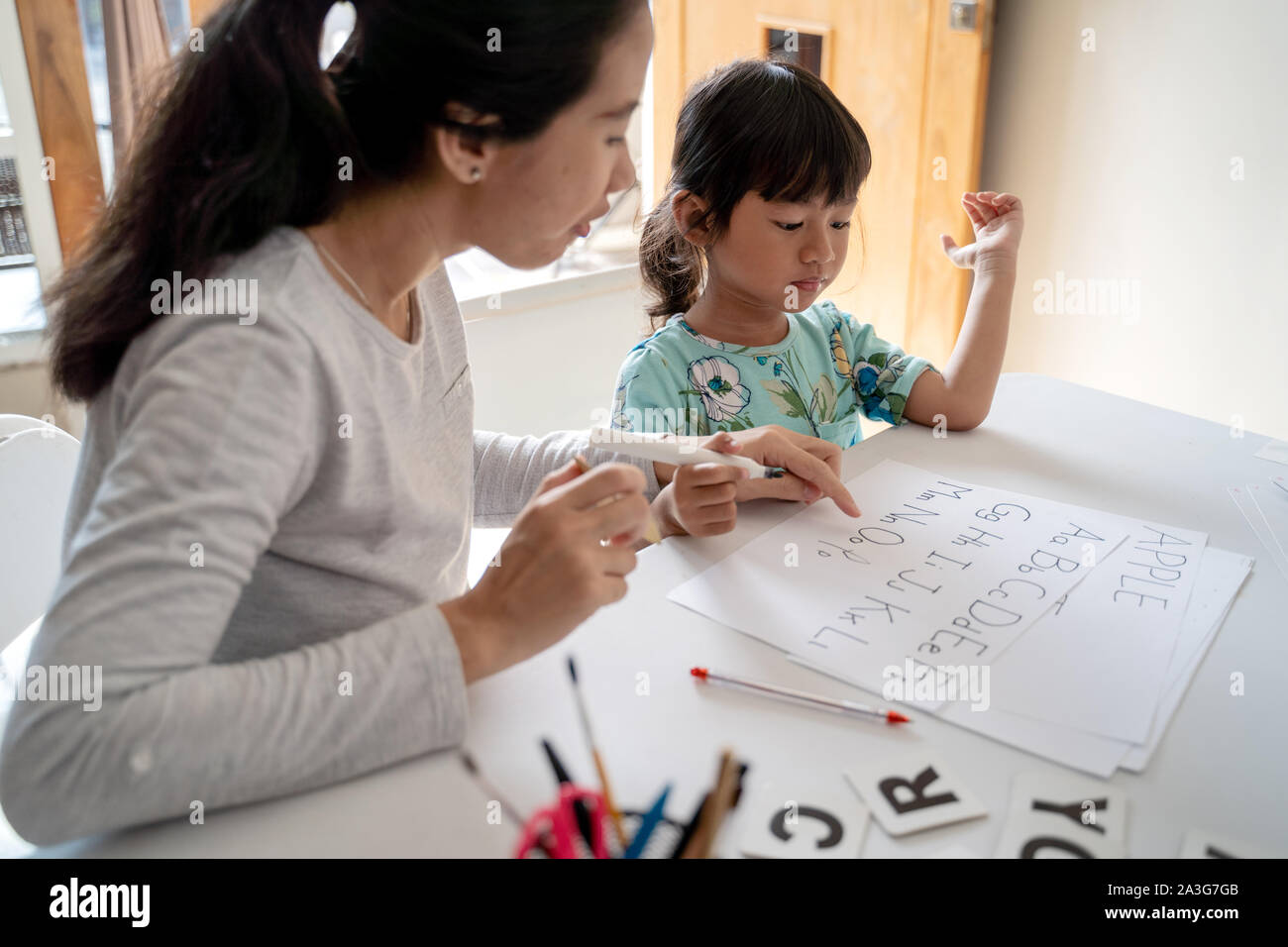 mother and daughter learning to read and write letter at home together