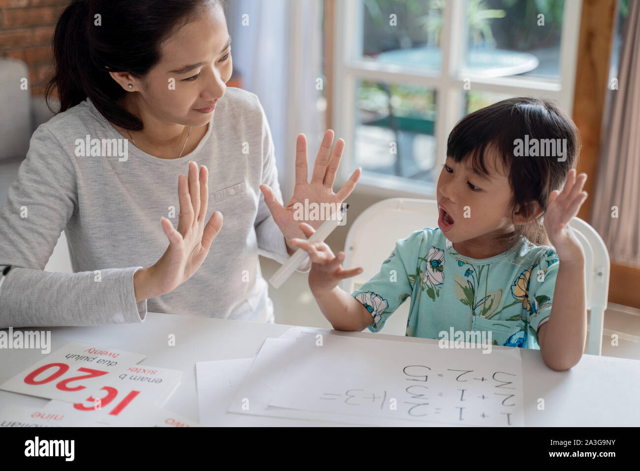 Mother teaching basic math to her little daughter at home stock photo