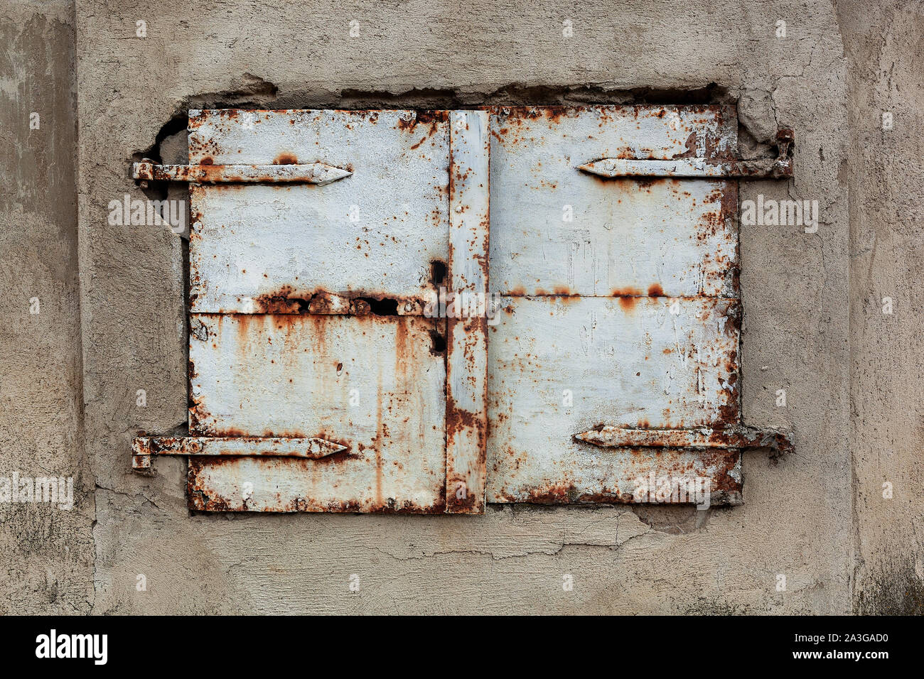 Old, rusty and weathered metal window coverings, closed shut on building exterior Stock Photo