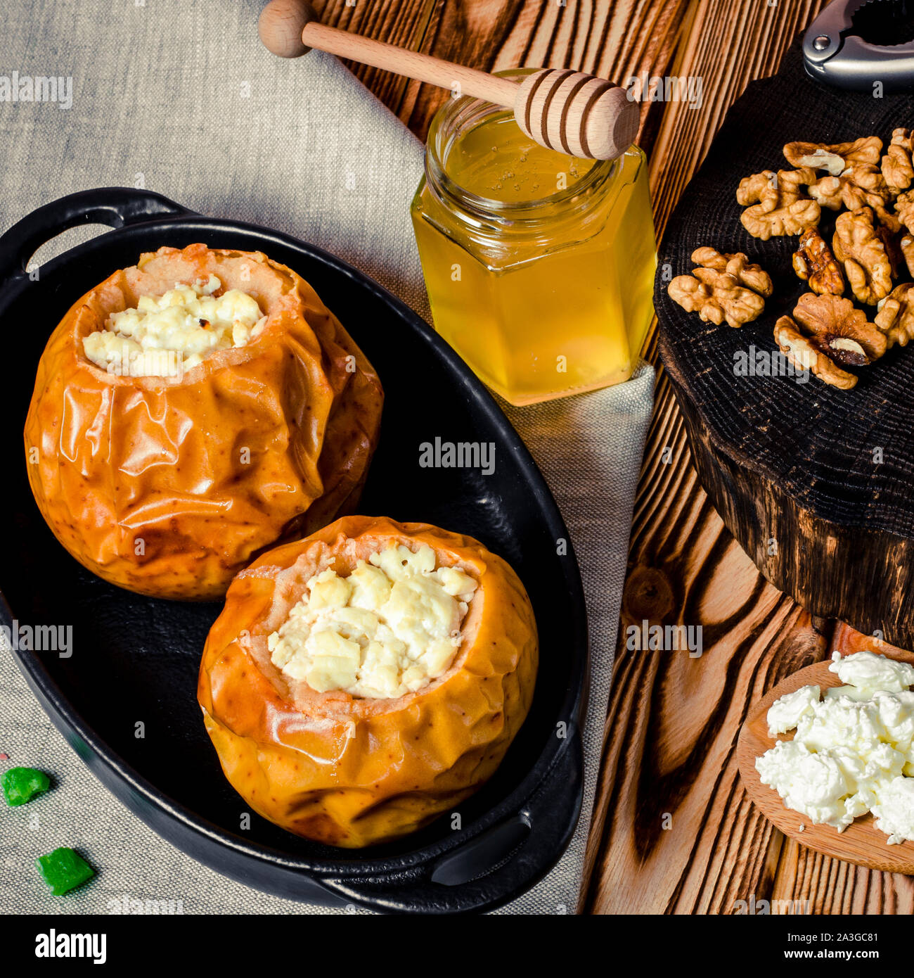 healthy food. Baked apples with cottage cheese and nuts lie in a black baking dish on a wooden table Stock Photo