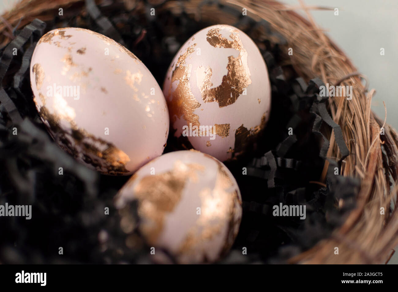Painted and gold foiled easter eggs in a nest. Moody tones, top view. Idea of a modern easter celebration. Stock Photo
