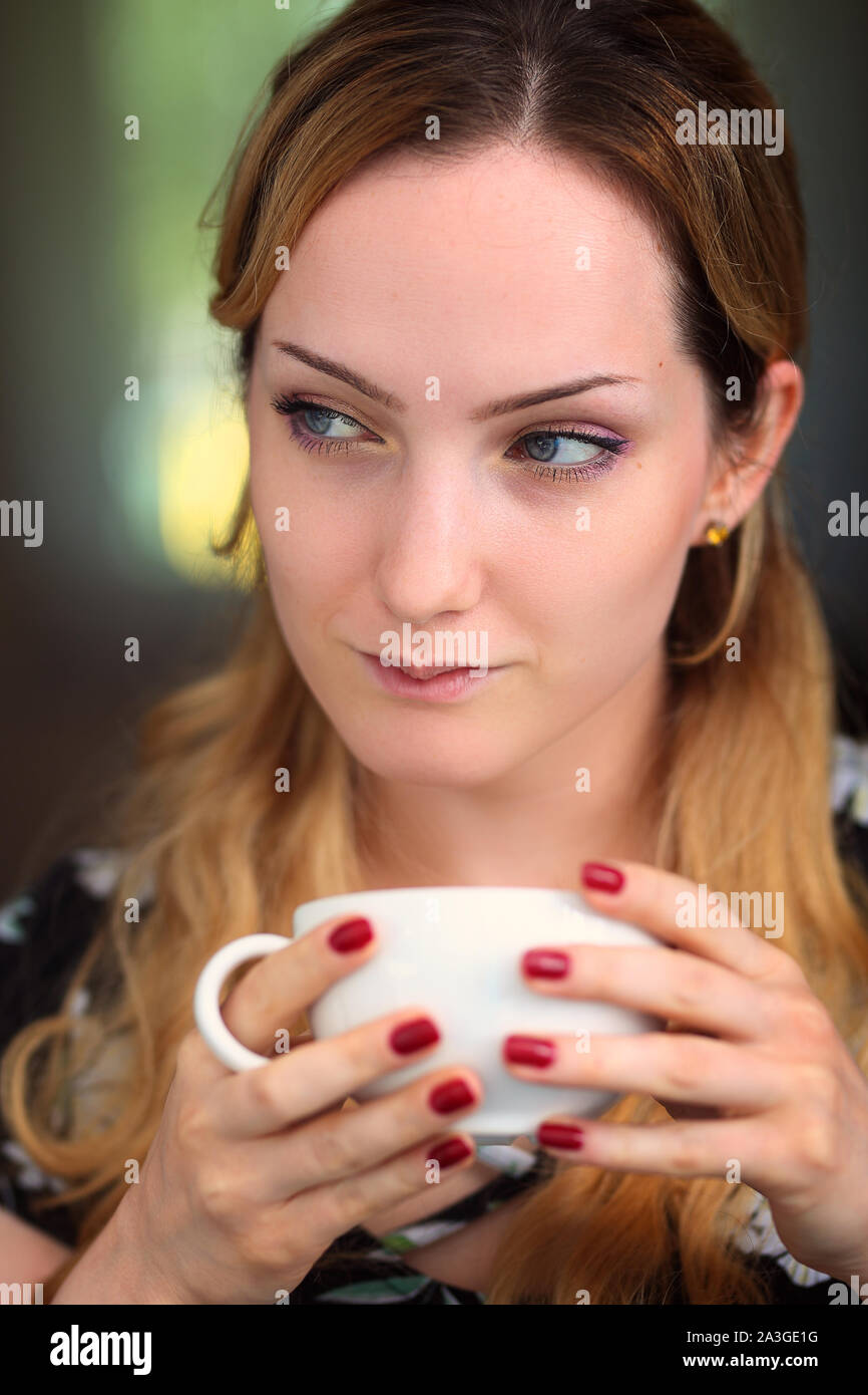 pensive and smiling woman with a cup of coffee Stock Photo