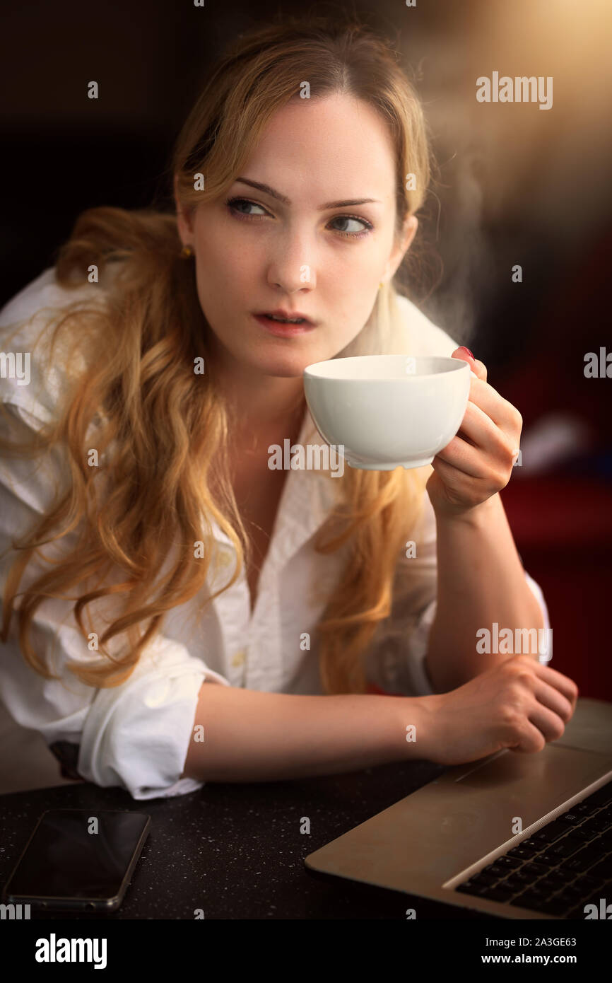 pensive woman with coffee at the computer at home Stock Photo