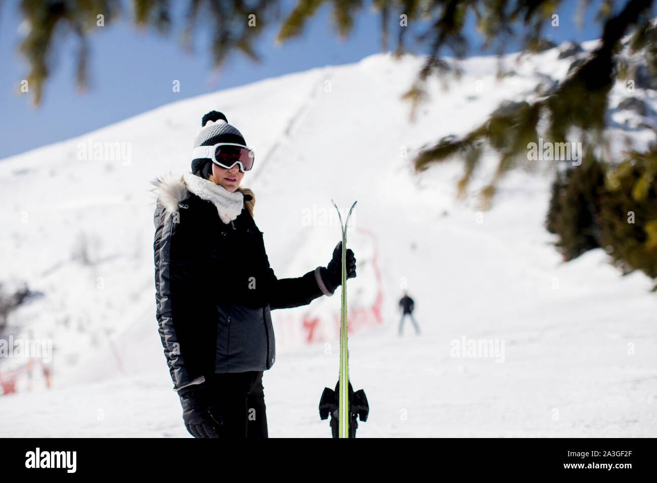 Happy young woman with ski equipment spending winter vacation at mountain resort Stock Photo