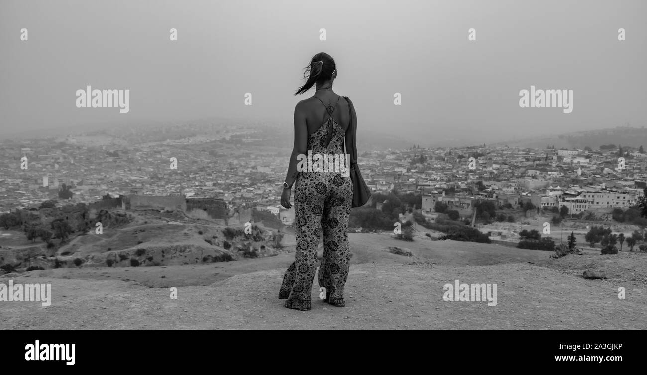 A black and white picture of a young female overlooking a panoramic view of Fes el Bali. Stock Photo
