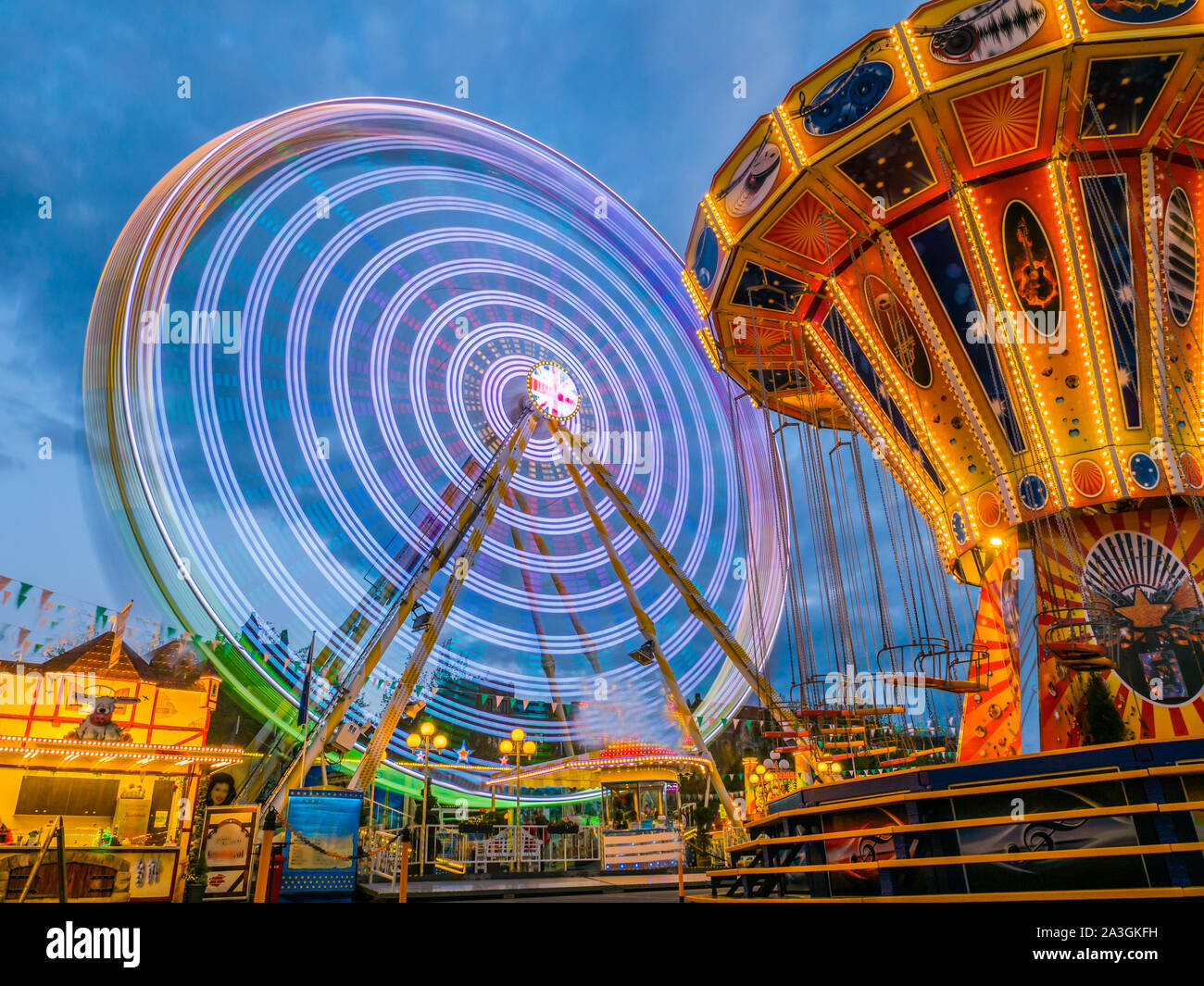 Ferris wheel and chain carousel in the evening at the fair Stock Photo