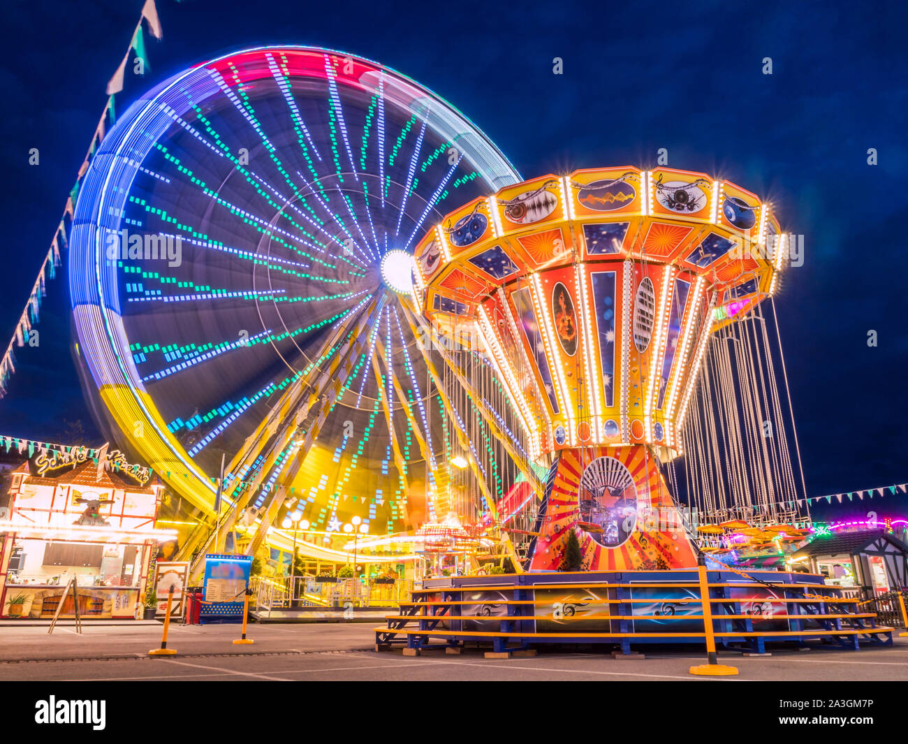 Ferris wheel and chain carousel in the evening at the fair Stock Photo