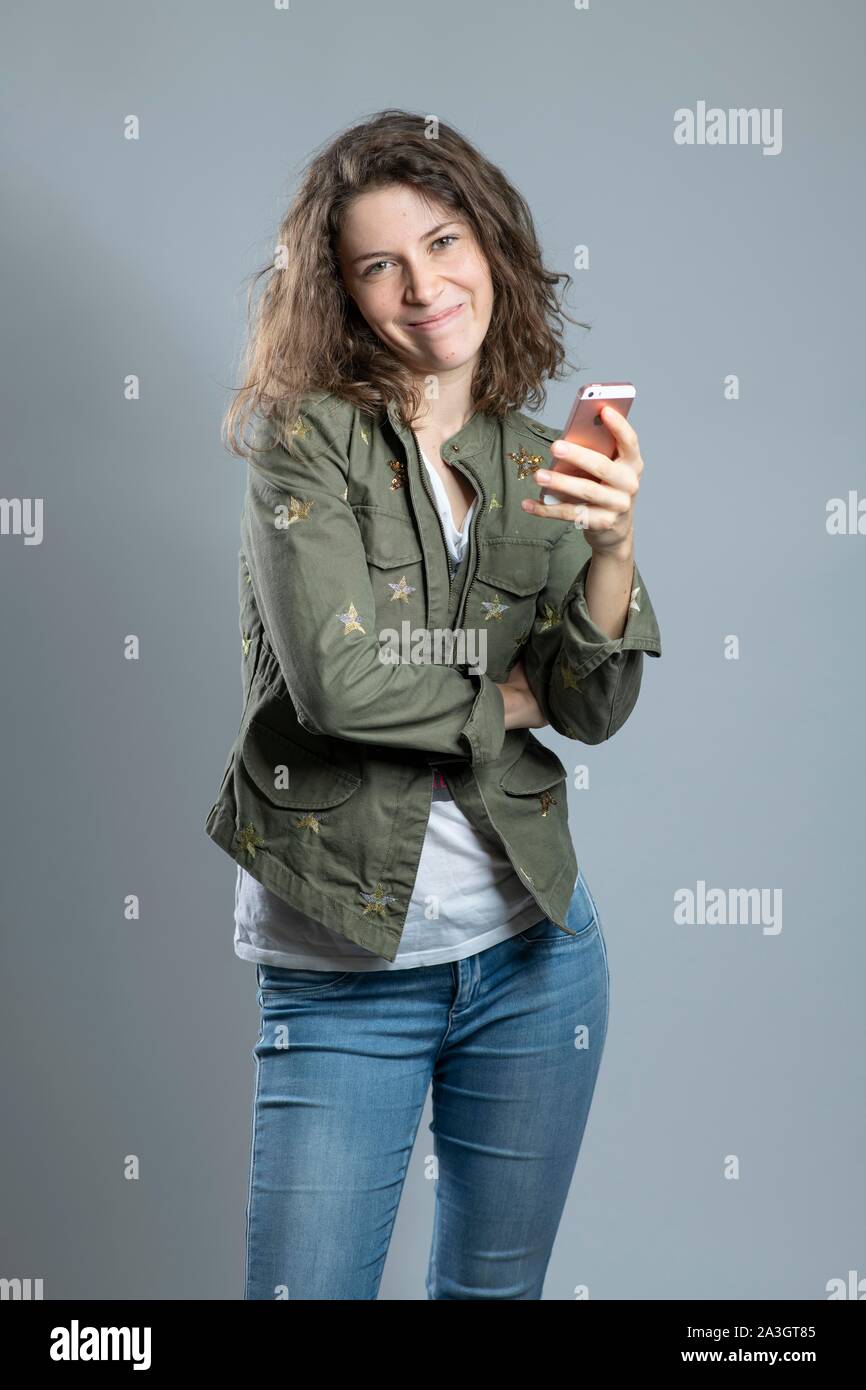 Young brown-haired woman with long curly hair with smartphone, Germany Stock Photo