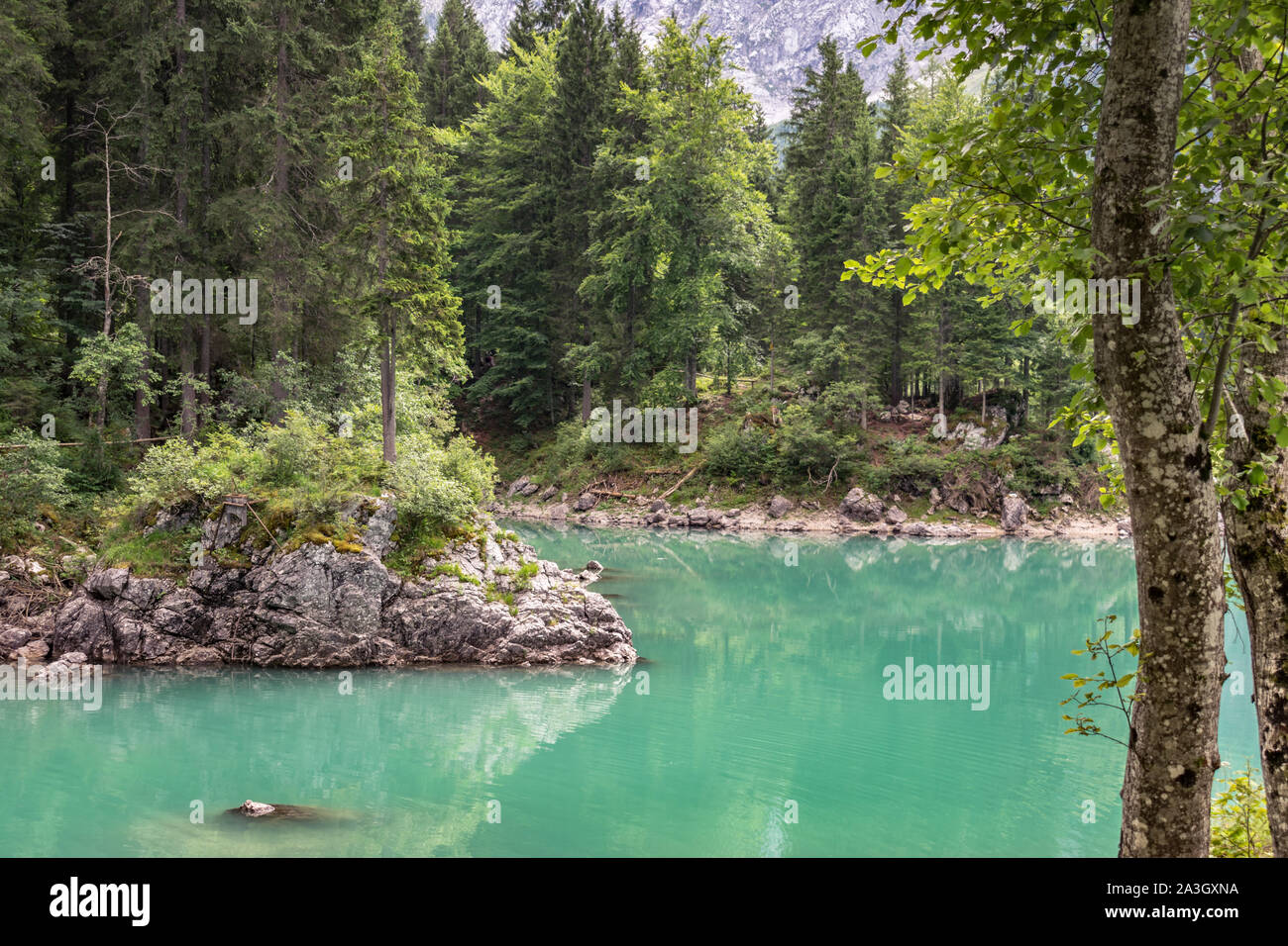 Clear turquoise colored water of Fusine Lake in Italian Alps. The lakes are in an area that is part of the Julian Alps, close to border with Slovenia. Stock Photo
