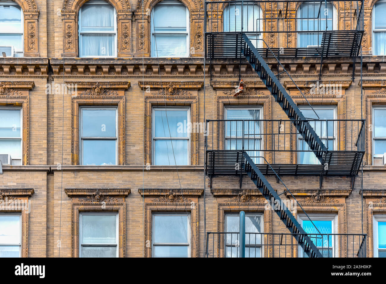 Yellow brick facade, and pair of boots hanging of the fire stairs. Chelsea, NYC. Stock Photo
