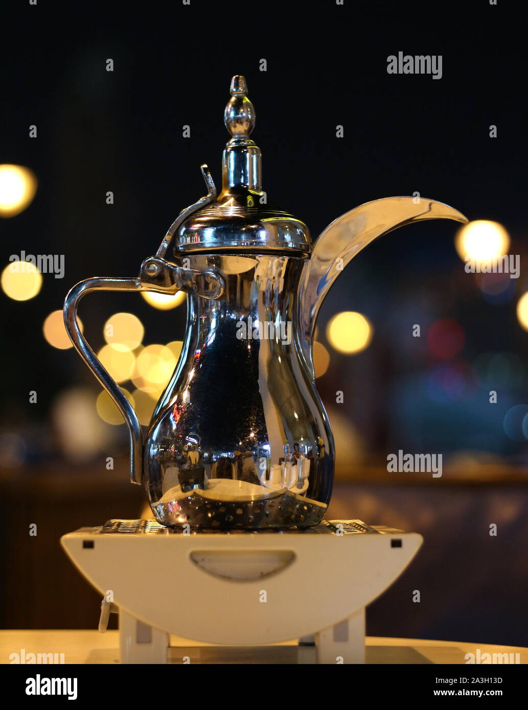 Traditional shiny Arabic coffee pot with long spout  bokeh background Stock Photo