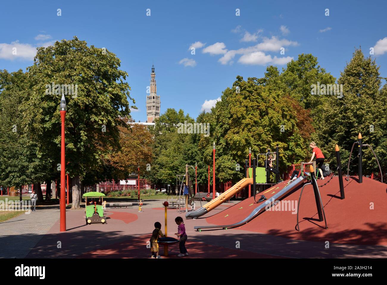 France, Nord, Lille, Jean Baptiste Lebas park with characteristic red  grilles dominated by the belfry listed as World Heritage by UNESCO and  which houses the services of the town hall, children's playground