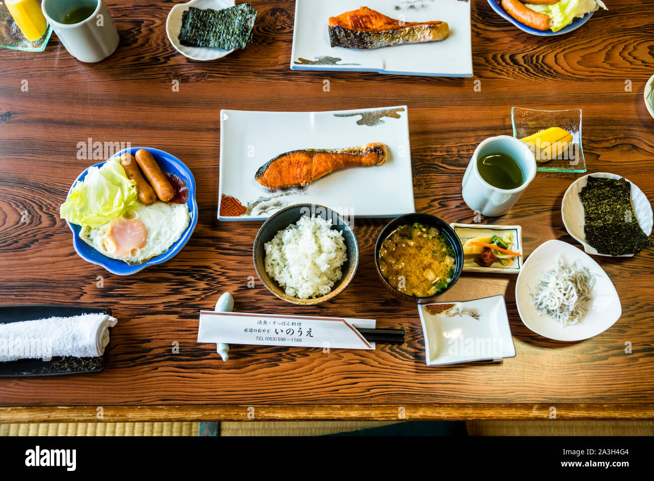 Grilled salmon, rice, miso soup and side dishes are arranged for a traditional Japanese breakfast, a name card for the Inoue restaurant standing beside them, ryokan on Lake Hamana near Hamamatsu, Japan. Stock Photo