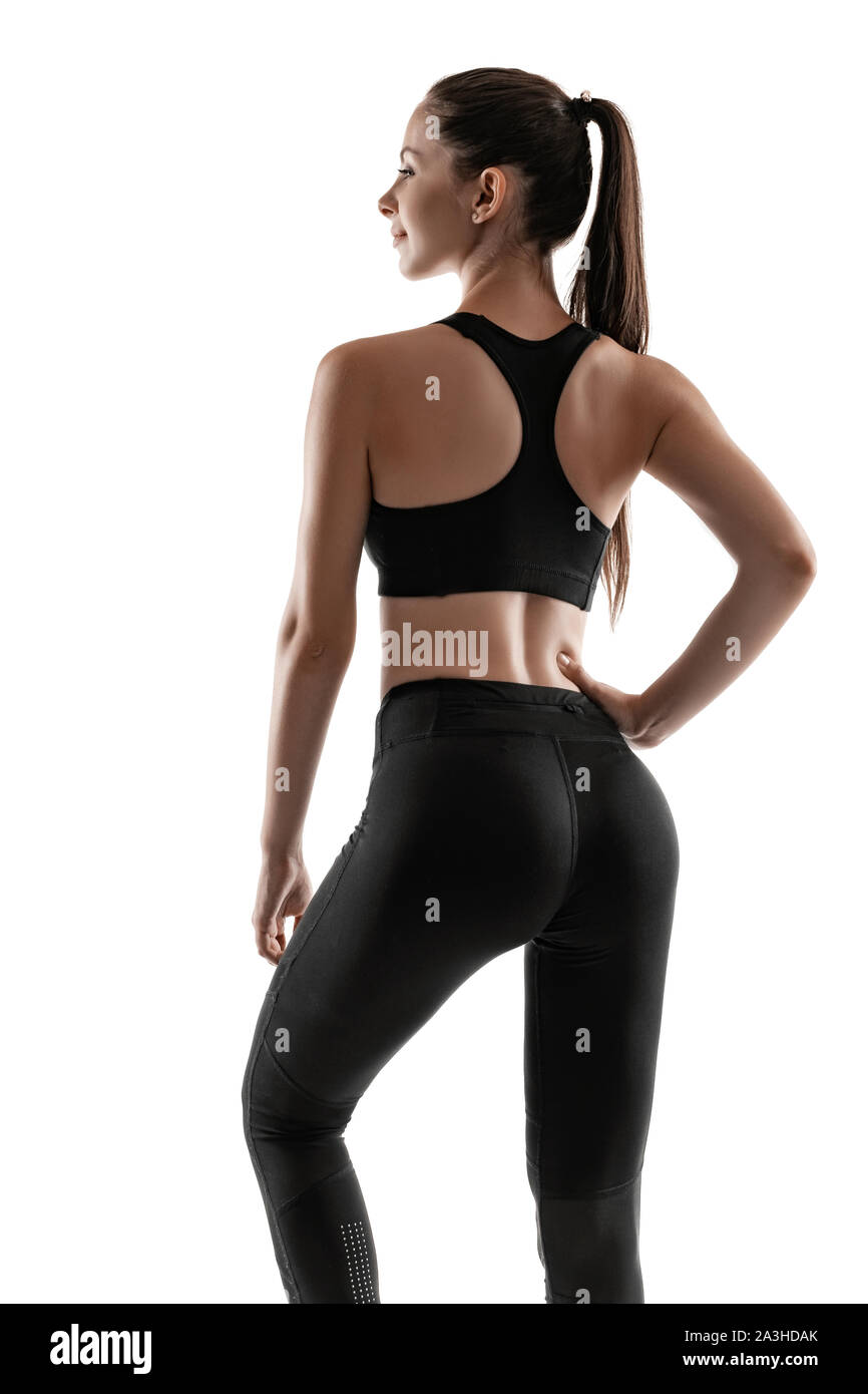 Brunette woman in black leggings top and sneakers is posing