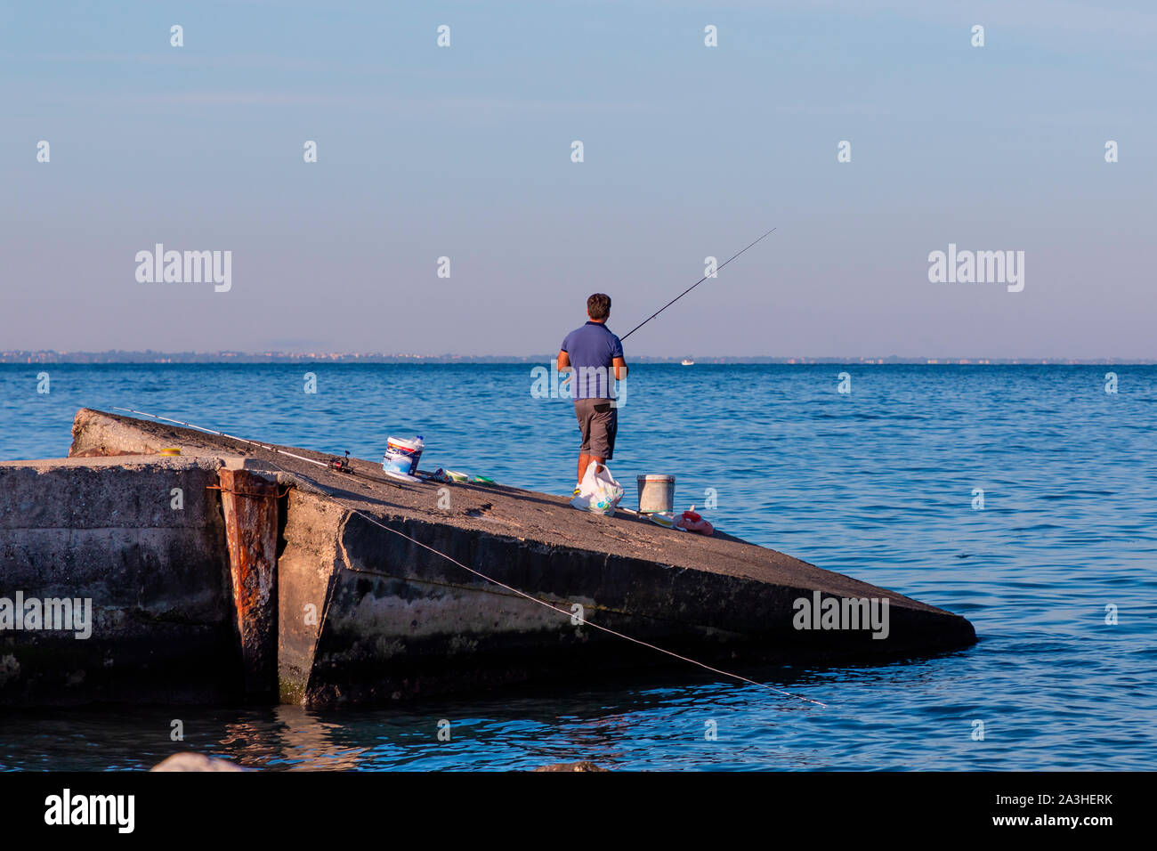 Fishing on a concrete boat ramp in Patras in Greece in the sunshine. Stock Photo