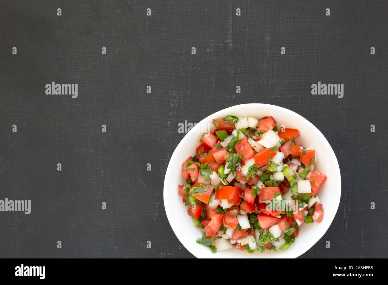 Pico de Gallo in a white bowl on a black background, top view. Overhead, from above, flat lay. Copy space. Stock Photo