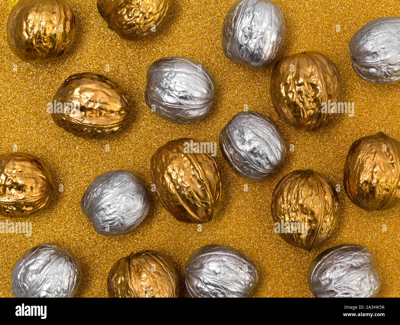 Painted golden and silver walnuts on glittering background Stock Photo