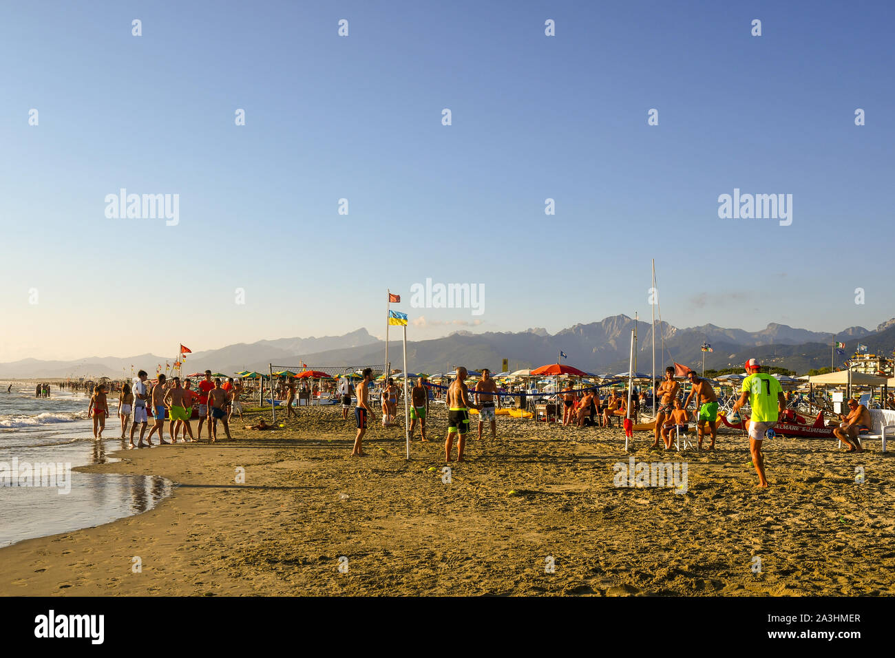 Scenic view of the beach of Lido di Camaiore with vacationers playing footvolley and beach volleyball in a sunny August day, Versilia, Tuscany, Italy Stock Photo