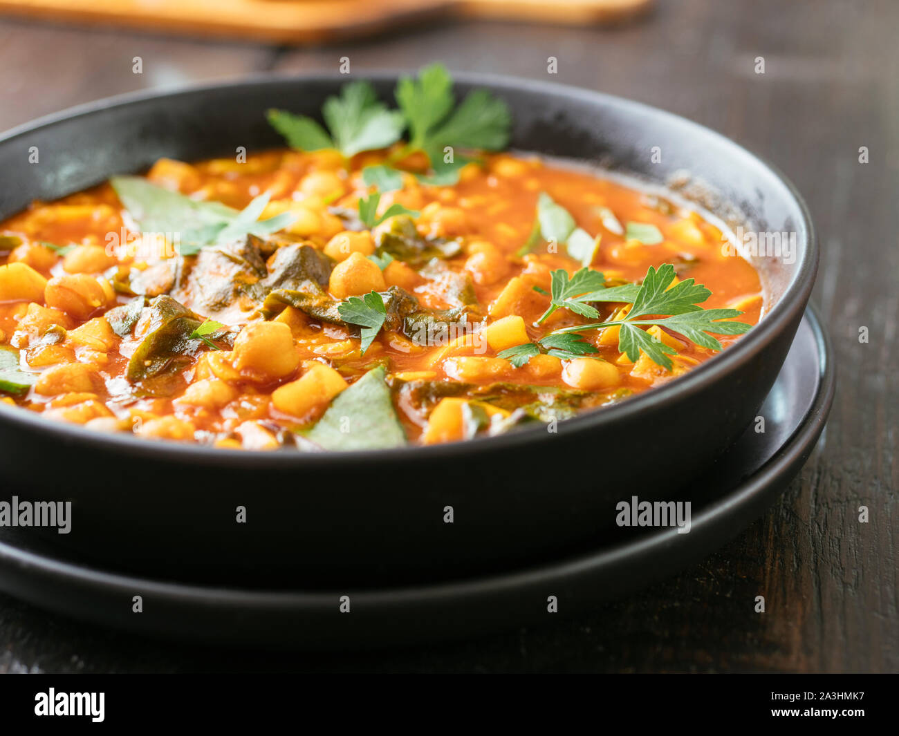 Bowl with a home made tomate and chickpea soup with malabar spinach. Stock Photo