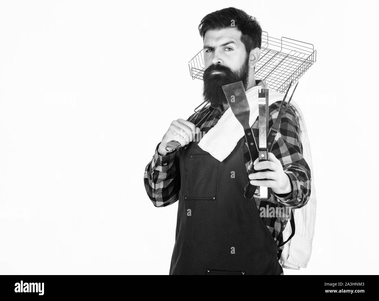 The best bbq in the city. Grill cook holding portable bbq tools. Bearded man with bbq grid and cooking tools in hands. Hipster using metal tools for preparing and serving bbq food, copy space. Stock Photo