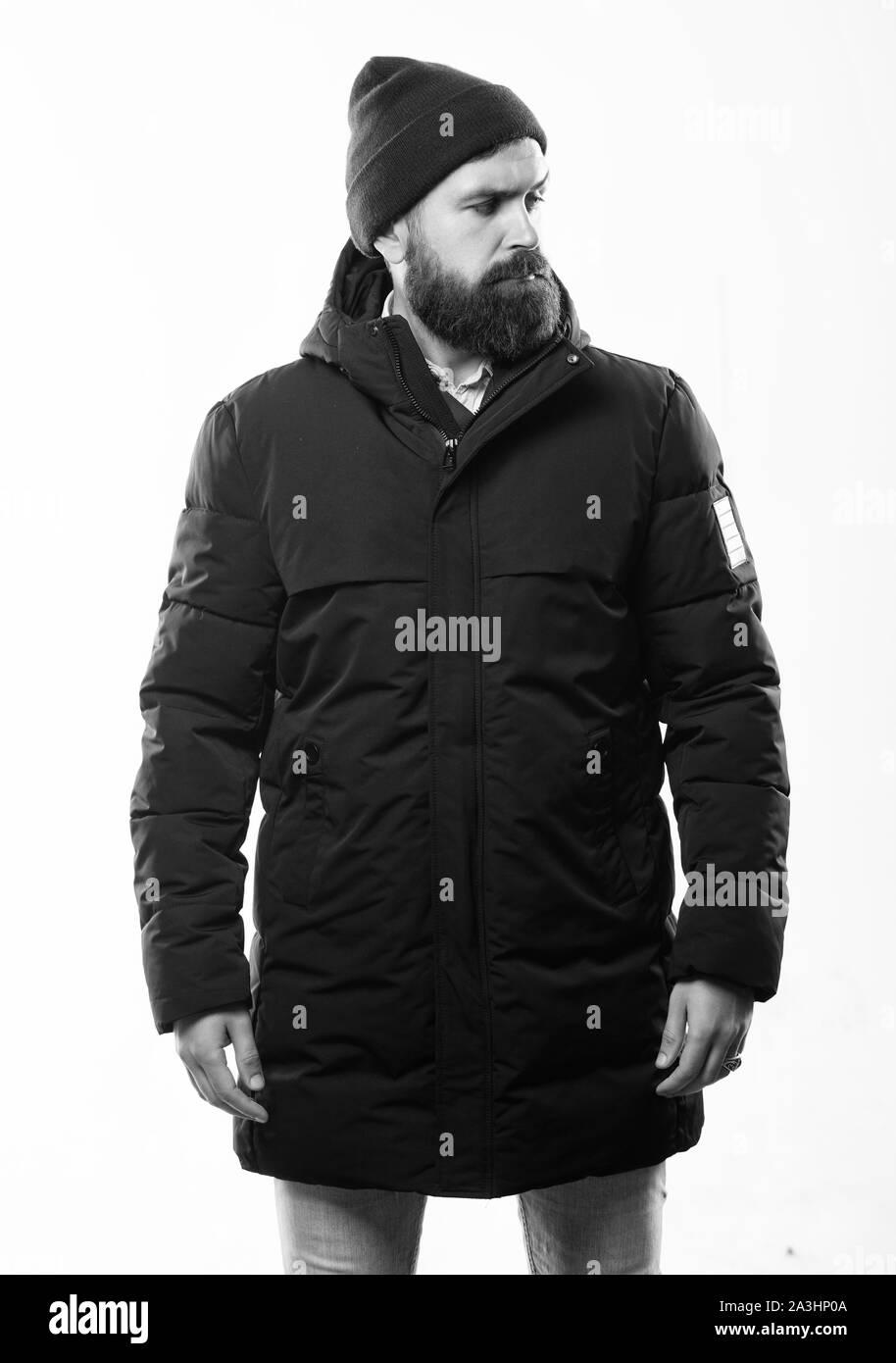 Hipster outfit. Stylish and comfortable. Man bearded hipster posing  confidently in warm black jacket or parka. Hipster modern fashion. Guy wear  hat and black winter jacket. Hipster style menswear Stock Photo -