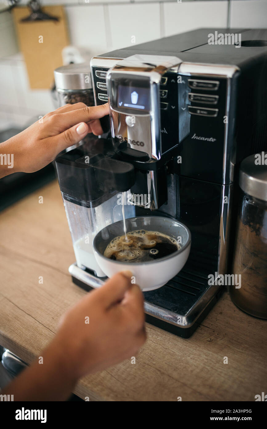 Young woman making coffee with milk 