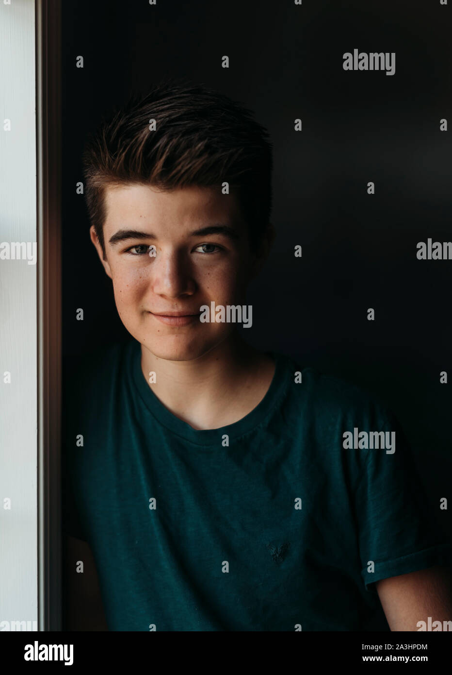 Portrait of a caucasian teenage boy against a dark background. Stock Photo