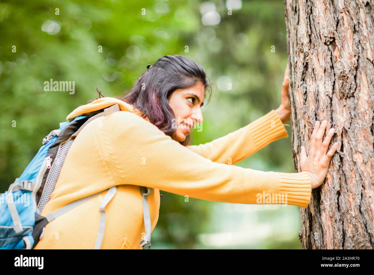 young woman pushing a tree with force Stock Photo Alamy