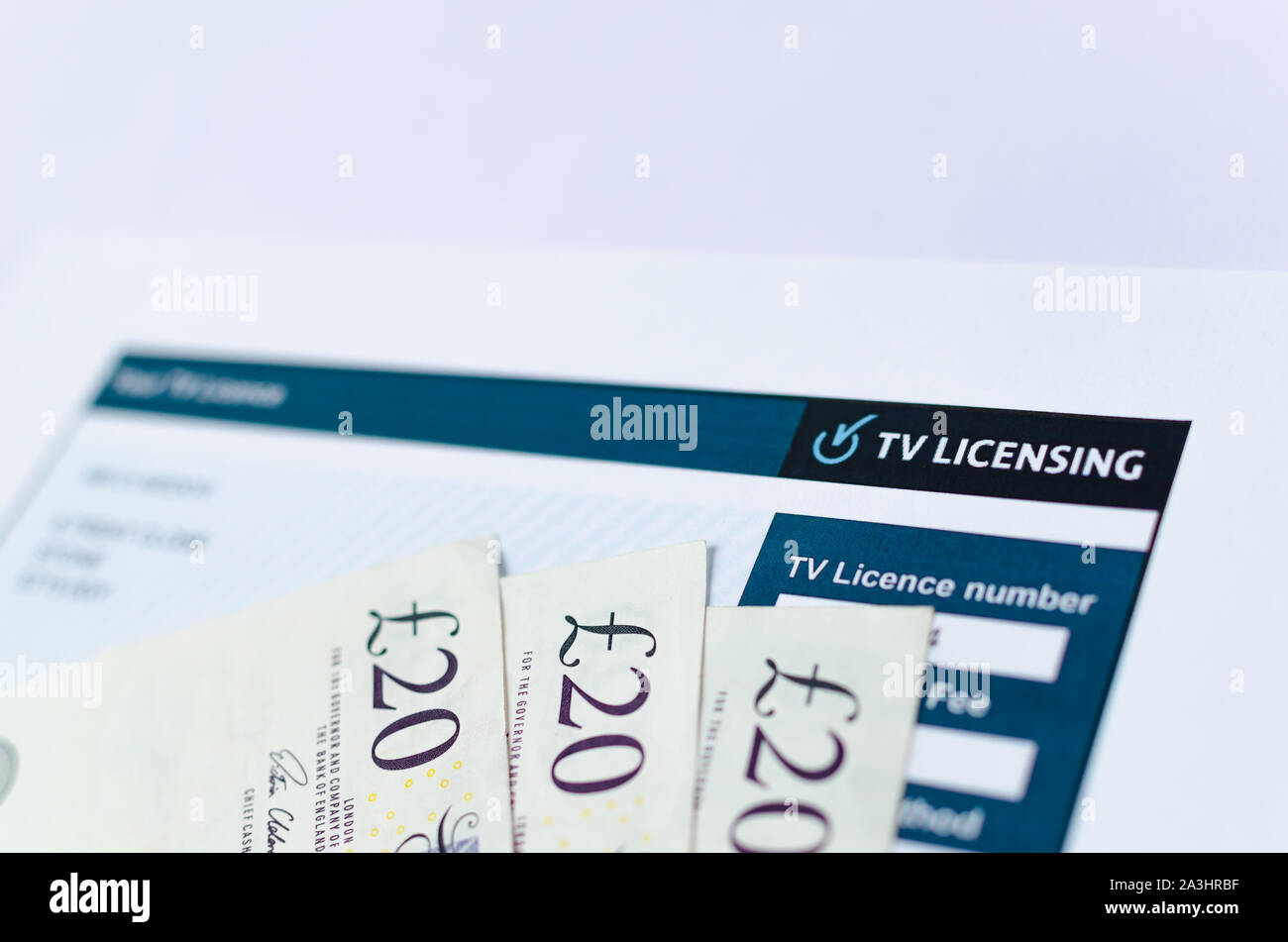 Close up photo of UK TV license with 20 pound notes. TV Licensing for every household in the UK with TV. Stock Photo