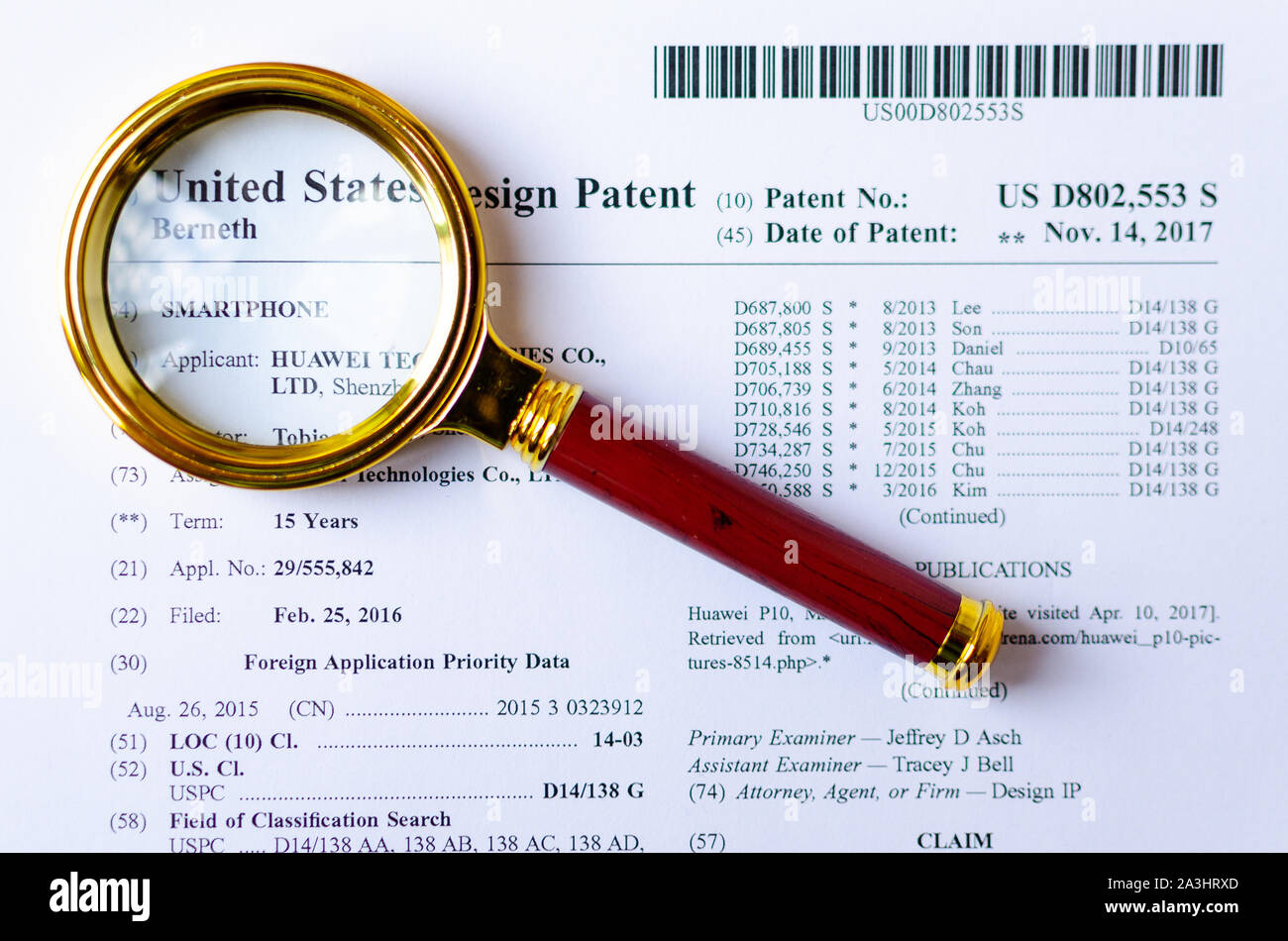 The close up photo of HUAWEI US patent and magnifying glass. Chinese technologies are under investigation. Stock Photo