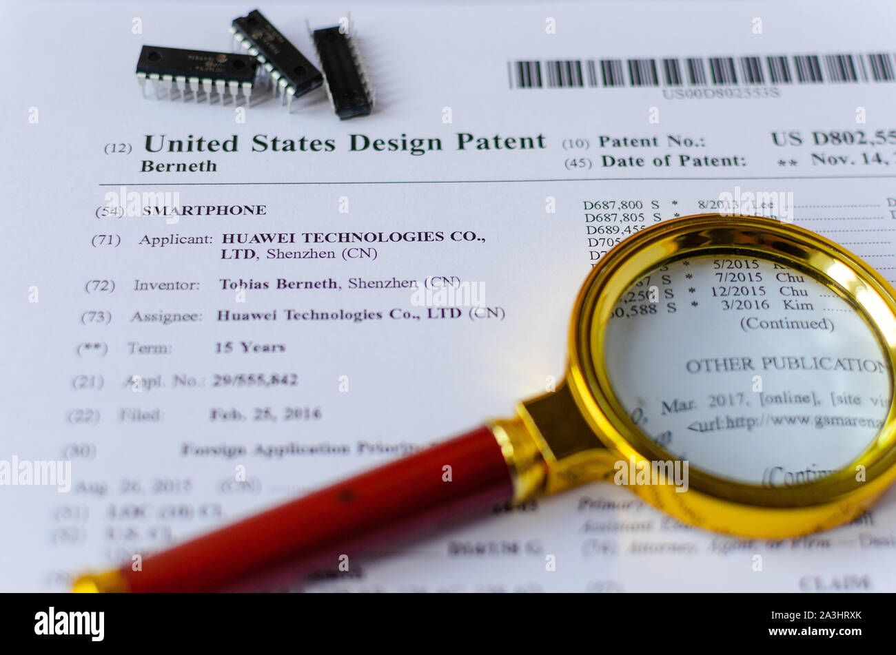 The close up photo of HUAWEI US patent, magnifying glass and microchips. Chinese technologies are under investigation. Stock Photo