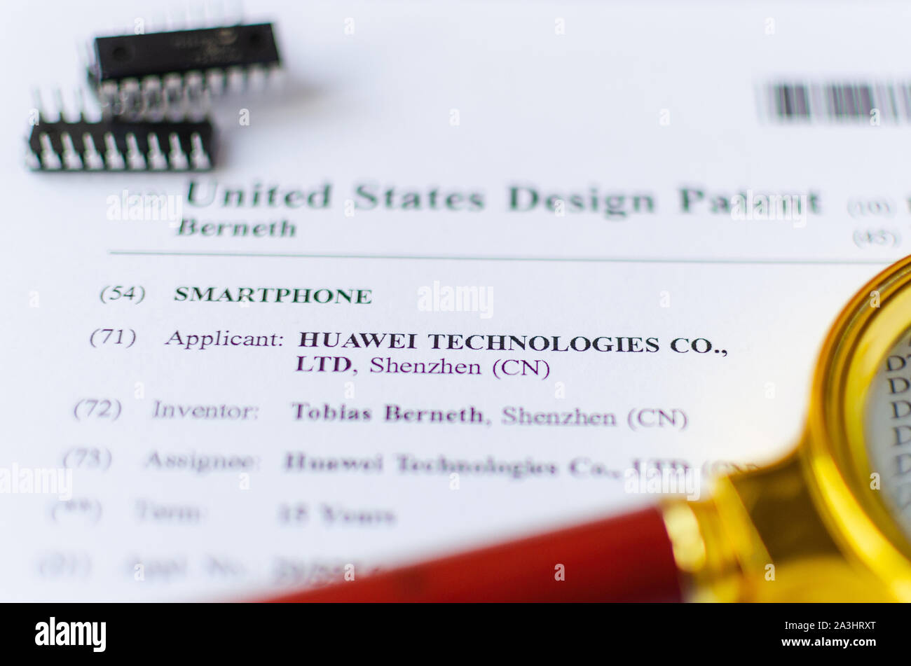 The close up photo of HUAWEI US patent, magnifying glass and microchips. Chinese technologies are under investigation. Stock Photo
