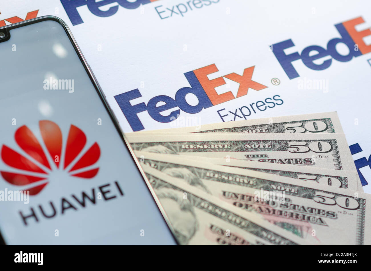 Huawei smartphone with logo on FedEX parcel logo with US dollars.This conceptual photo illustrates USA - China trade war and current investigations Stock Photo