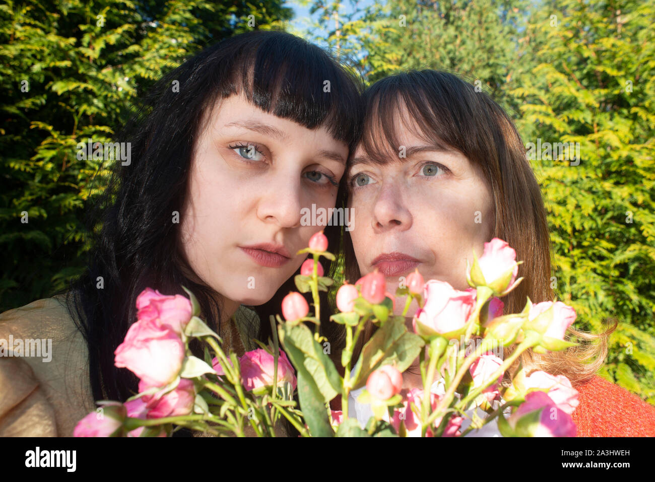 Head and Shoulders Portrait of Two Women, Heads Touching, with Bouquet of Flowers Stock Photo