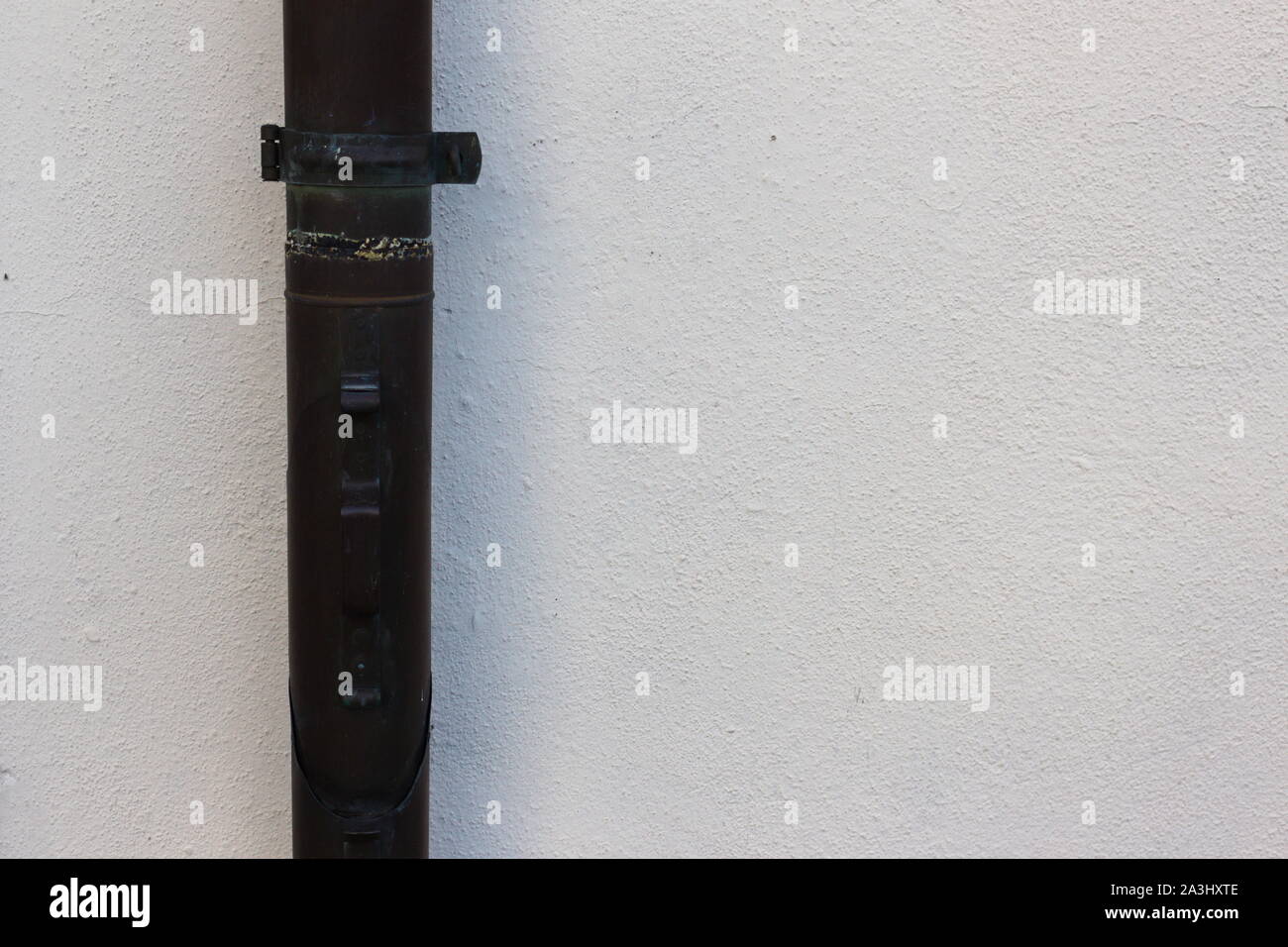 White wall with a rain water downpipe with a flap to collect the water on it Stock Photo