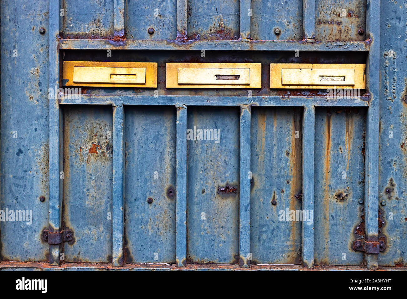 Rusty metallic door with three golden mail boxes  Stock Photo