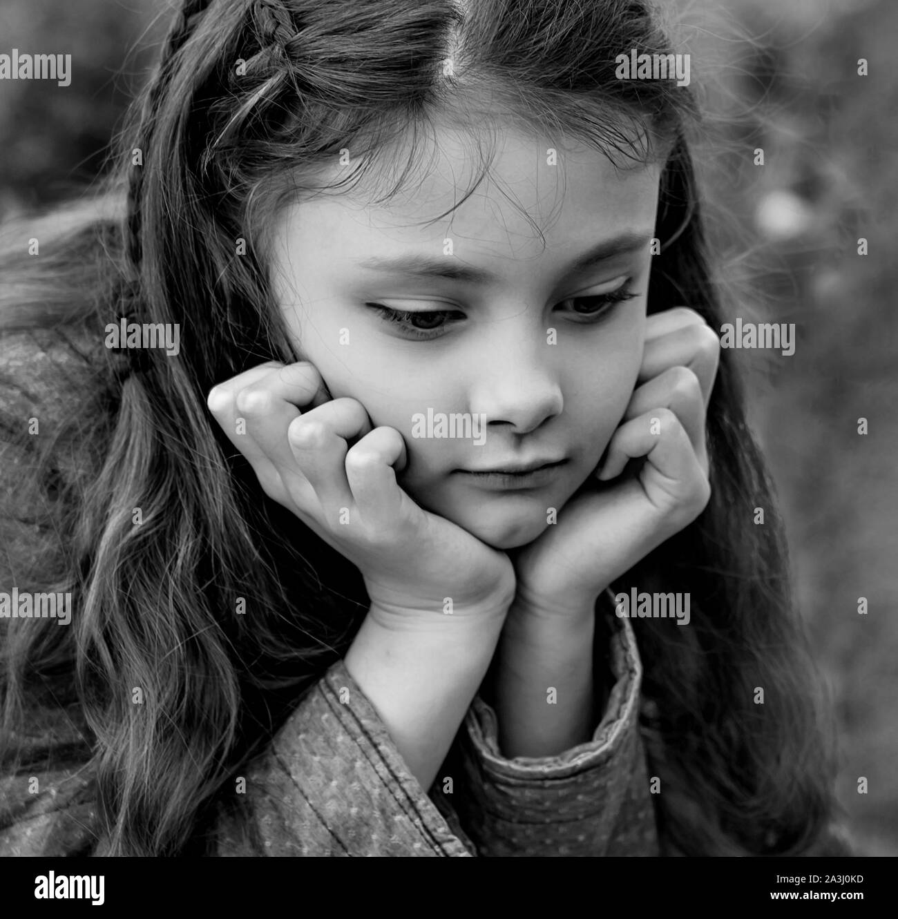 Unhappy kid girl with beautiful hair looking down with sad eyes ...