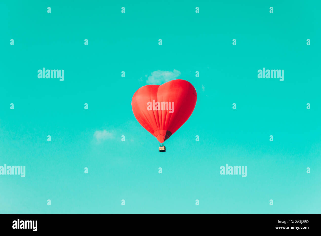 Red hot air balloon in the shape of a heart against the blue sky and ...