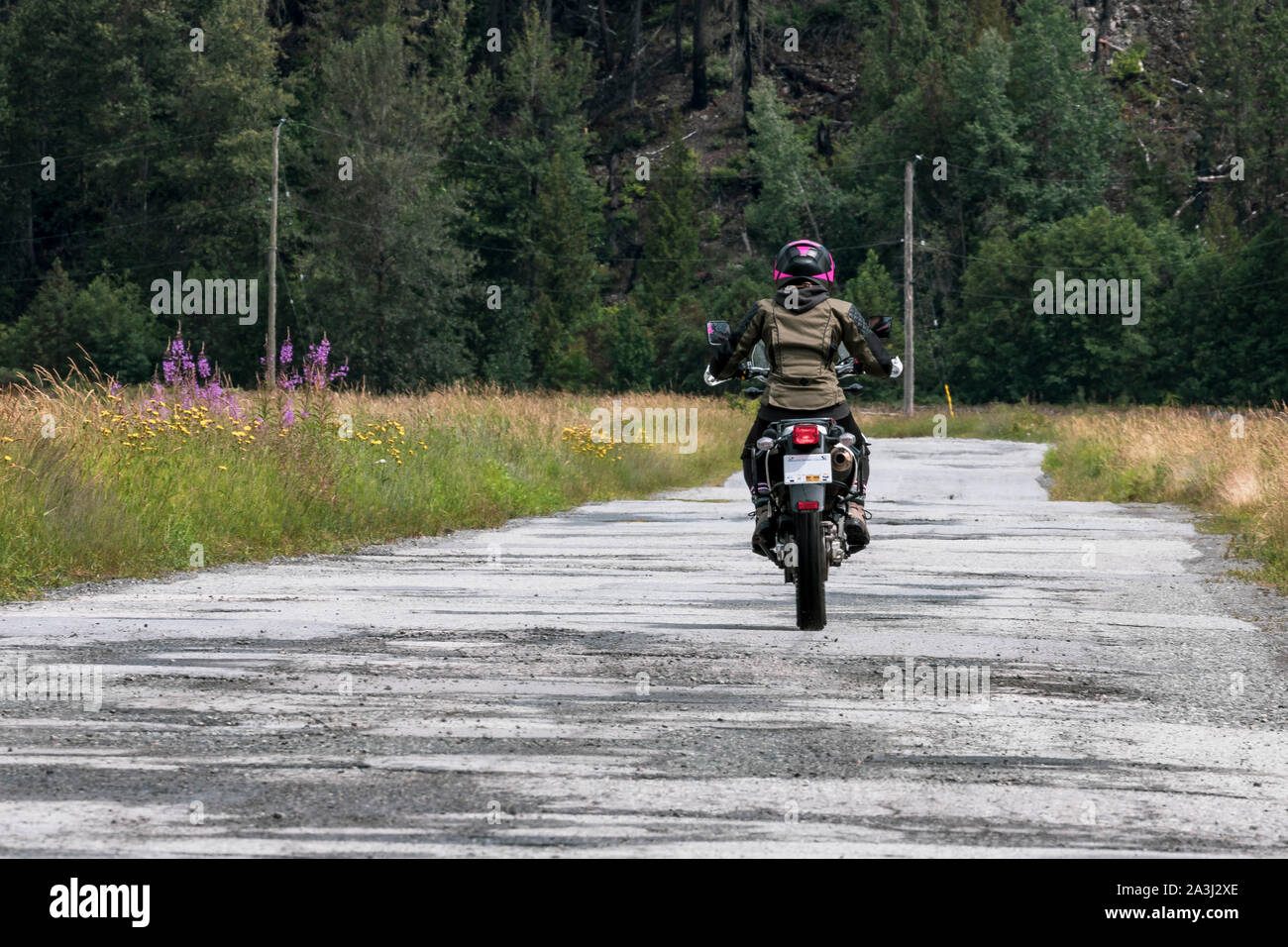 A woman rides her motorcycle on a cloudy summer day. Stock Photo