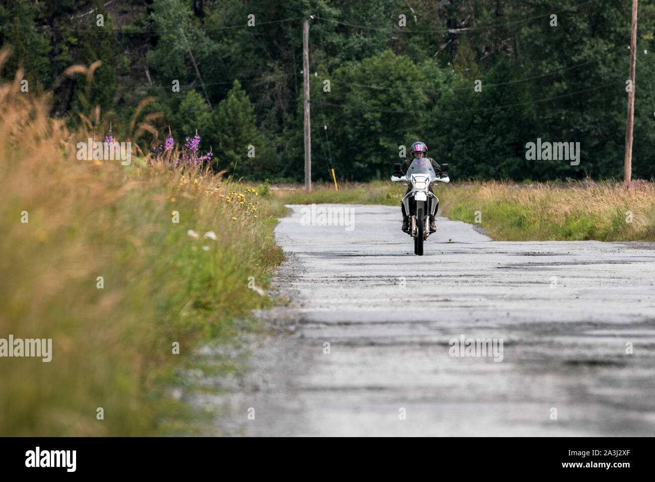 A woman rides her motorcycle on a cloudy summer day. Stock Photo