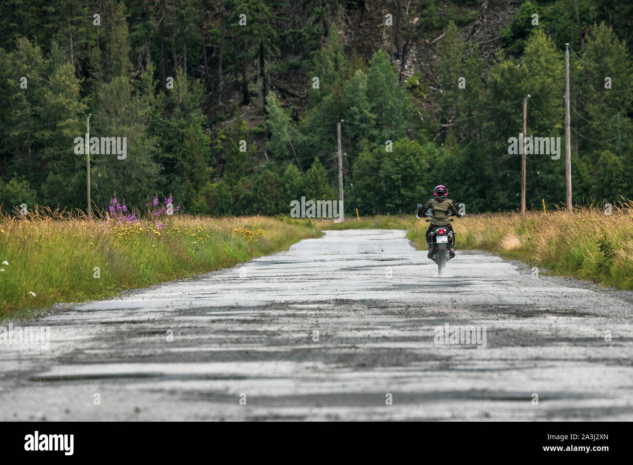 A woman rides her motorcycle on a cloudy summer day. Stock Photo