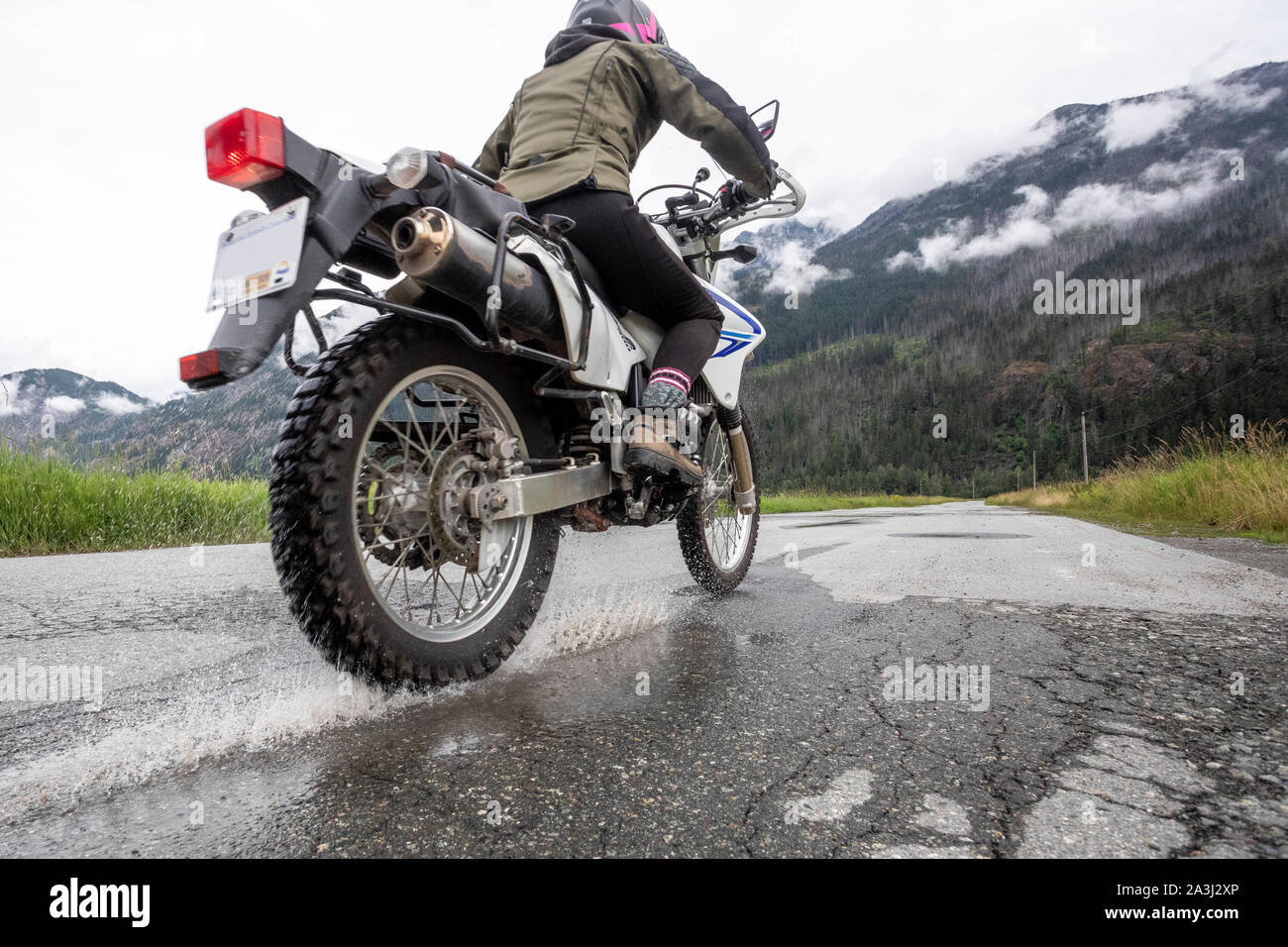 A woman rides her motorcycle on a cloudy summer day. Stock Photo
