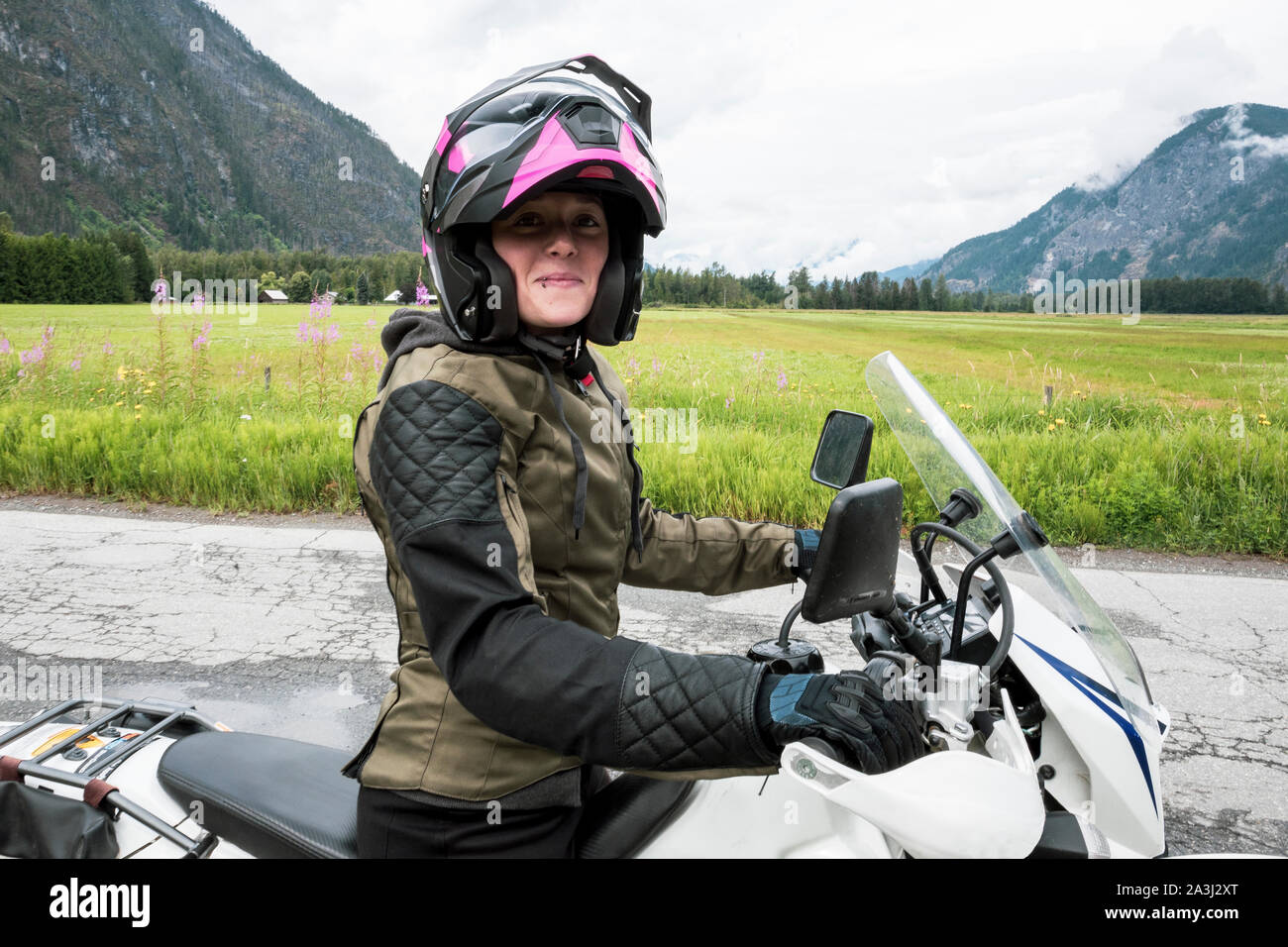 A woman rides her motorcycle on a cloudy summer day. Stock Photo