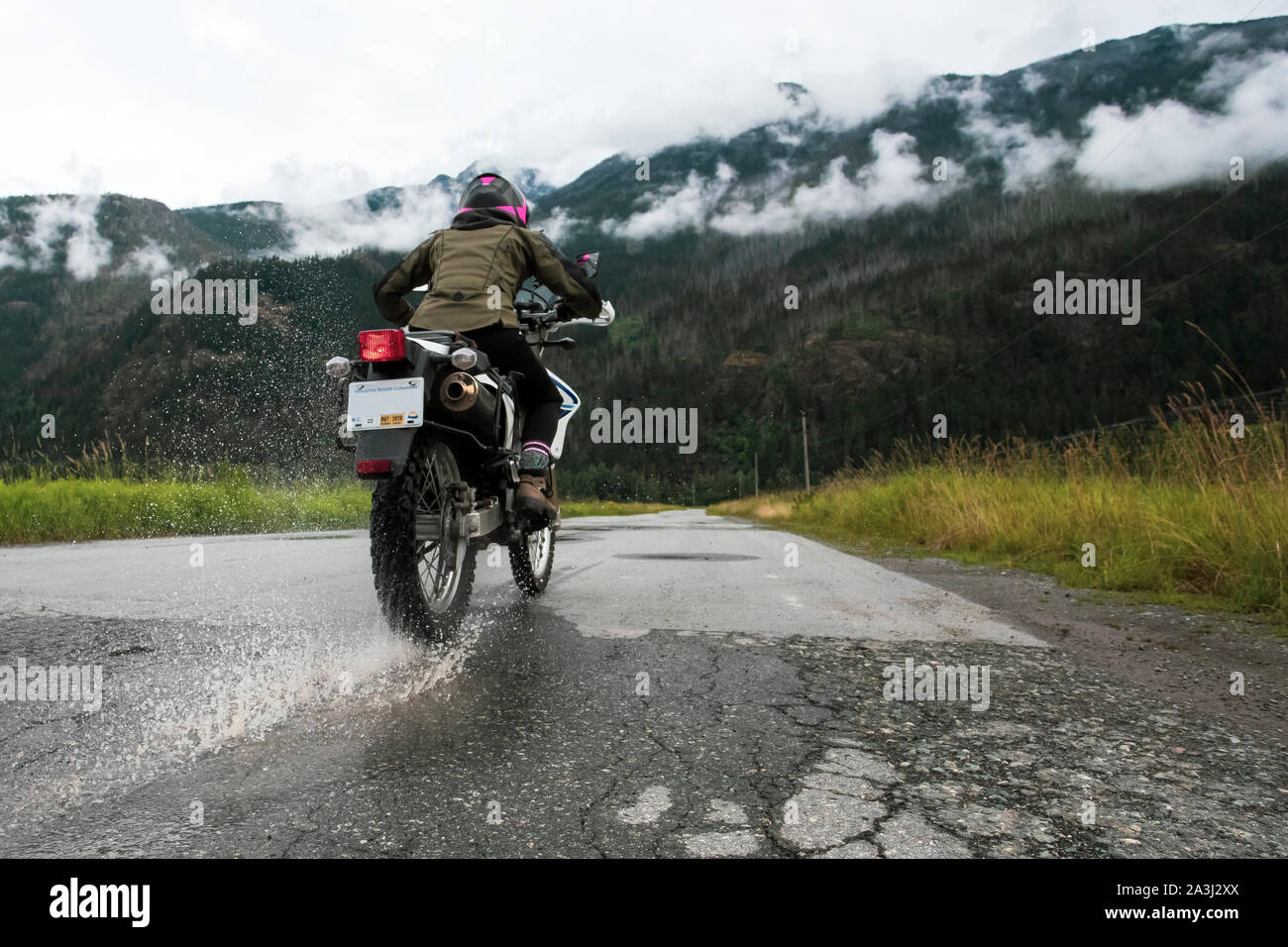 A woman rides her motorcycle on a cloudy summer day. Stock Photo