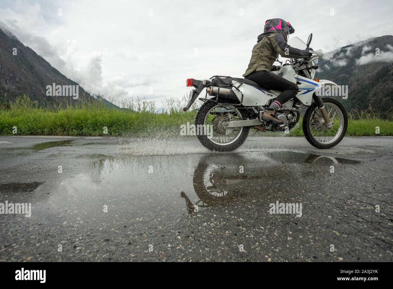 A woman rides her motorcycle on a cloudy summer day. Stock Photo