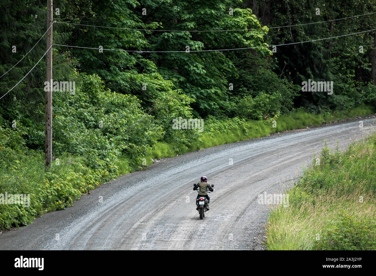 A women rides her motorcycle on a gravel road in Canada. Stock Photo