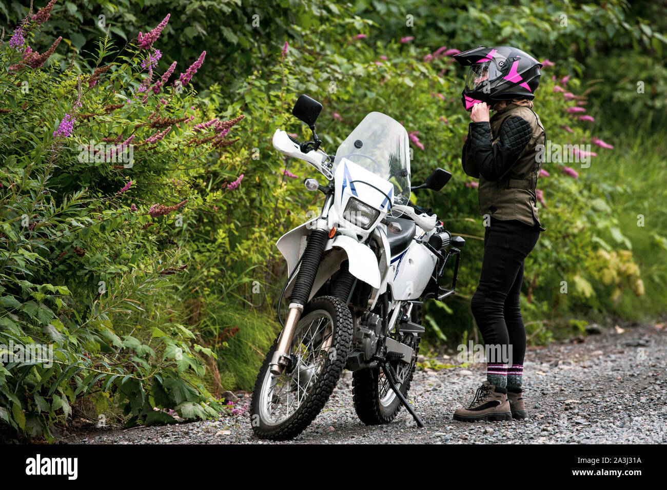 A women takes a break from motorcycle riding and takes off her helmet. Stock Photo