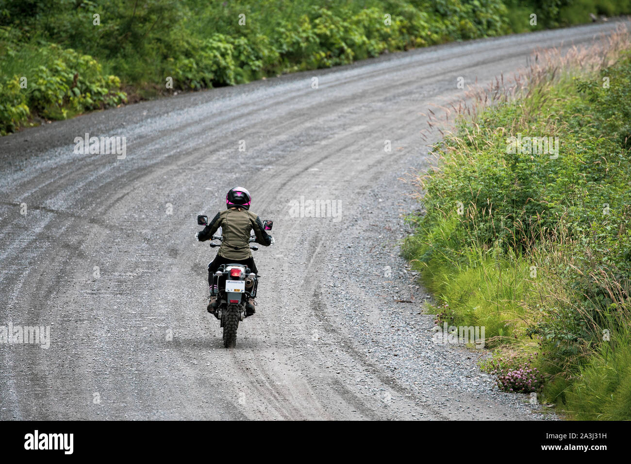 A women rides her motorcycle on a gravel road in Canada. Stock Photo